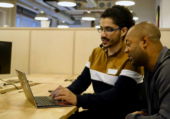Two trainees working together at a laptop